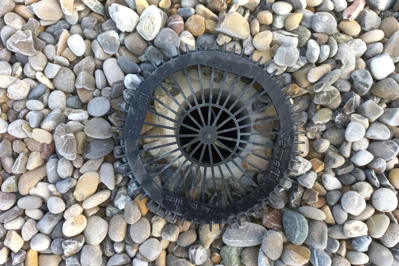 A rainwater outlet set into the gravel ballast of a flat roof